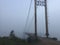 Misty suspension bridge fog view. Altai village bridge. Early misty morning