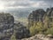 Misty valley with dry trees along sharp sandstone massives