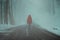 Misty winter road and red cloaked person