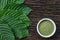 Mitragynina speciosa or Kratom leaves with powder product in white ceramic bowl and wooden table background