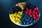 Mix of colored berries in a round plate divided by triangles. Stylish layout of useful vitamins of summer berries