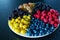 Mix of colored berries in a round plate divided by triangles. Stylish layout of useful vitamins of summer berries