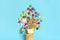 Mix colorful chocolate sweets spilled out of ice cream waffle cone on blue background