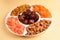 Mix of dried fruits and nuts on a white plate. Apricot, almond, raisin, dates fruit. On a beige background. Space for text or