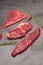 A mix of marbled beef steaks garnished with rosemary and chili pepper. Vertical photo