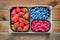 Mix of organic berries. Baskets of fresh raspberries, blueberries,strawberries on wooden table