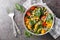 Mix salad of fresh spinach, corn, cherry tomatoes and onions with olive oil dressing close-up in a bowl. Horizontal top view