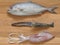 Mix seafood, black-banded trevally fish, tiger prawn, and cuttlefish, on wooden cutting board background