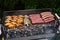 Mixed assortment of marinated meat, chicken, and prawns grilling on hot coals on a BBQ