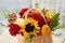 Mixed autumn flowers in basket, bouquet is on the windowsill.