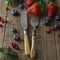 Mixed berries, blueberry, strawberry on wood background with vintage, styled fork and knife. Styled food, fruit background.