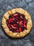 Mixed berries summer pie on a dark background, top view. Red, black currant, strawberry, raspberry sweet pie