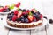 Mixed berry cheesecake tart with chocolate on light sunny background. Generative AI