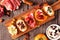 Mixed crostini appetizers with a variety of toppings, top view table scene over wood