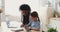Mixed ethnicity mom and school child daughter studying at home