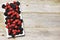 Mixed forest fruits as blackberry and raspberry on rectangular white plate, on rustic wooden background