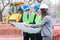 Mixed group of architects and business partners discussing project details on a construction site