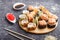 Mixed japanese maki sushi rolls set with chopsticks, ginger, soy sauce,rice on black concrete background, side view