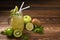 Mixed lime, kiwi, apple juice with slice fruits in jug on wood
