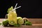 Mixed lime, kiwi, apple juice with slice fruits in jug on wooden table