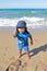 Mixed little toddler boy showing sand on beach by sea