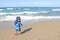 Mixed little toddler boy standing on beach by sea