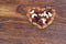 A Mixed nuts and dried fruits forming a heart-shape on wood background