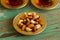 Mixed nuts on a metal saucer and two glass cups of Turkish tea on a turquoise wooden background.