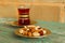 Mixed nuts on a saucer and a glass cup of Turkish tea on a turquoise wooden table on the background of a brick wall.