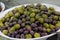 Mixed olives sprinkled with herbs in a white bowl