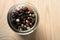Mixed Peppercorns in Glass Container on Light Wood Background