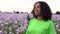 Mixed race African American girl teenager female young woman walking in field of pink poppy flowers