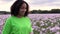 Mixed race African American girl teenager female young woman walking through field of pink poppy flowers