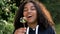 Mixed race African American girl teenager girl young woman blowing dandelion at sunset