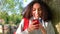 Mixed race African American girl teenager leaning against a tree using cell phone