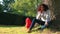 Mixed race African American girl teenager leaning against a tree using a cell phone camera for social media