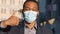 Mixed race businessman in suit wears medical face mask. Close-up focus on hand showing thumbs up gesture. Preventive