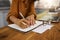 Mixed race businesswoman writing in a notebook while working from home. One hispanic female businessperson taking notes