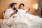 Mixed-race couple with mobile phones in hotel room