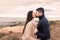 Mixed race couple romance scene on sea rocks and cloudy sky at sunset or dawn - Handsome bearded guy kisses his beautiful black