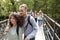 A mixed race couple and young adult friends crossing a wooden bridge over a river during a hike