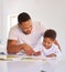 Mixed race father teaching little son during homeschool class at home. Cute little hispanic boy learning how to read and