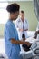 Mixed race female doctor in patient room preparing to checking blood pressure of male patient