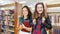 Mixed Race Female Students Wearing Backpack and Books Walking in the Library