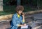 Mixed race girl with blue denim shirt speaks by her smartphone sitting in a park