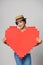 Mixed race girl in straw hat holding big paper pixel style heart shape with copy space for text