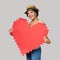 Mixed race girl in straw hat holding big paper pixel style heart shape with copy space for text