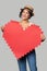 Mixed race girl in straw hat holding big paper pixel style heart shape with copy space for text