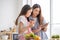 Mixed race girl younger and older sister talk and smile while play and using smartphone inside of the kitchen in the morning while