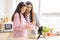 Mixed race girl younger and older sister talk and smile while play and using smartphone inside of the kitchen in the morning while